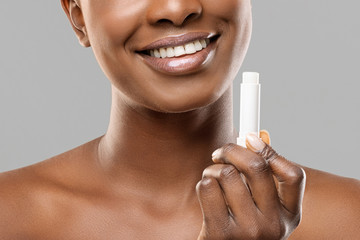 Moisturising lip balm in hands of unrecognizable african american woman - obrazy, fototapety, plakaty