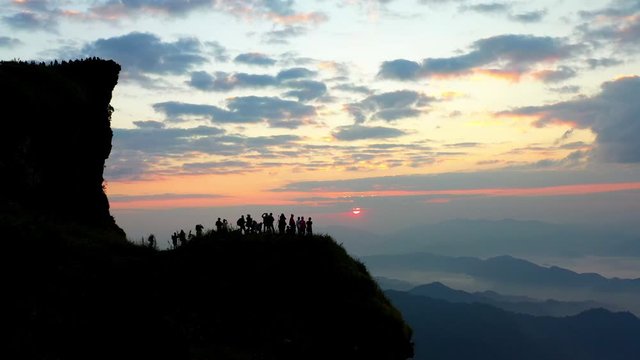 Aerial view of tourists' silhouettes and photographers taking pictures of beautiful misty scenery at the top of the mountain at sunrise. Phucheefah chiangrai, thailand