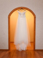 white wedding dress hangs on a hanger