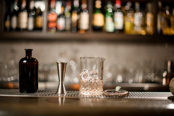 Bottle, jigger and glass with ice and alcohol