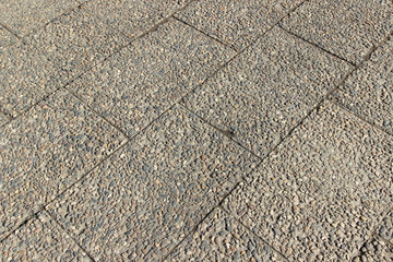 Sidewalk paved with rectangular tiles made of concrete and cobbles of various sizes and colors. Photo in perspective 