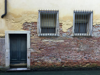 Door and windows of a stone house on a canal of Venice