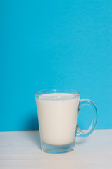 Glass of milk on a wooden table on a blue background