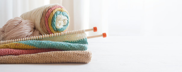 Knitting wool and knitting needles in pastel colors on white background. Cotton bolls. Copy space