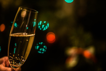 Glass with champagne in hand on a Christmas tree background