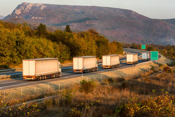 White trucks on a highway. Highway transportation with white lorry convoy