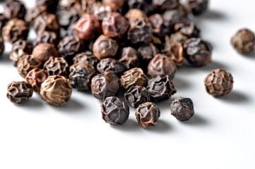 black allspice peppercorns close-up scattered on white  background