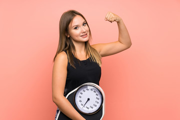 Teenager girl with weighing machine over isolated background