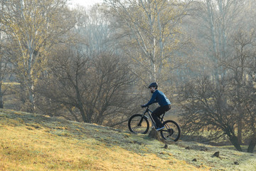 Cyclist in pants and fleece jacket on a modern carbon hardtail bike with an air suspension fork. The guy on the top of the hill rides a bike.