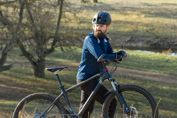 Cyclist in pants and fleece jacket on a modern carbon hardtail bike with an air suspension fork. The guy on the top of the hill rides a bike.