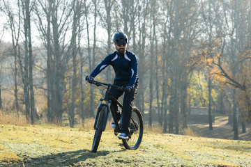 Fototapeta premium Cyclist in pants and fleece jacket on a modern carbon hardtail bike with an air suspension fork. The guy on the top of the hill rides a bike.