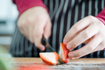 Close up image of man hands holding a knife and preparing fruit by slicing strawberries in kitchen for make Jam and Smoothie.Healthy lifestyle and Vitamins from fruits.
