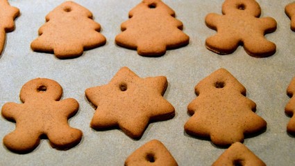 Christmas cookies. Homemade gingerbread cookies in various shapes  on the baking tray. Cookies freshly made at home, golden browned colored cookies before decorating with icing