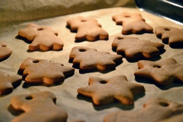 Christmas cookies. Homemade gingerbread cookies in various shapes  on the baking tray. Cookies freshly made at home, golden browned colored cookies before decorating with icing