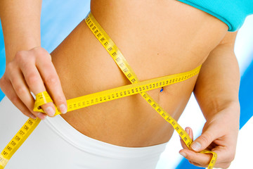 Healthy woman measuring her waist with a measuring tape