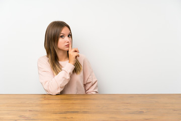 Teenager girl in a table doing silence gesture