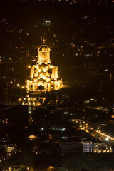 Fototapeta na wymiar Tbilisi, Georgia A scenic view at night of the city and the illuminated Holy Trinity Cathedral of Tbilisi