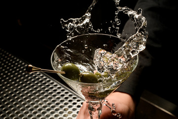Close shot of splashing alcohol with olives on toothpick