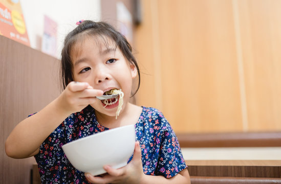 Happy Positive Funny Little Asian Girl Touching Holding Hands Of Full Stomach.She Eat Over Food And Full With Food In Restaurant.