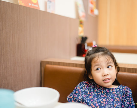 Happy Positive Funny Little Asian Girl Touching Holding Hands Of Full Stomach.She Eat Over Food And Full With Food In Restaurant.