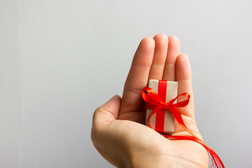 Female hand holding present gift box against grey background. Happy family celebrating concept for Valentine Birthday Christmas or New Years day