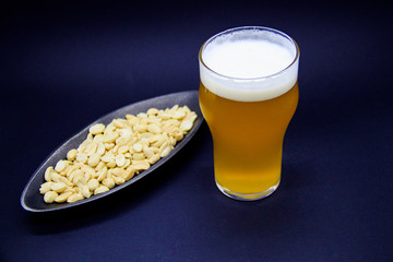 Craft beer and peanuts on black background