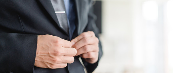 Obraz premium Closeup hands of business man fitting suit with tailor.Hands on button and try to fitting black suit.