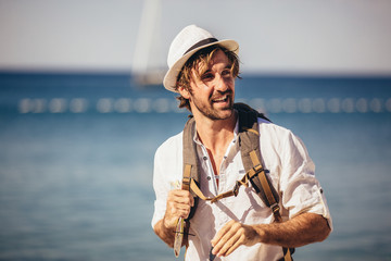 Outdoor fashion portrait of handsome stylish tourist guy posing at the beach.