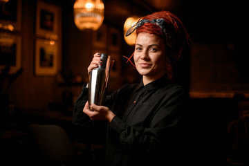 Portrait of cute female bartender in bandana with shaker