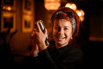 Portrait of smiling female bartender in bandana with shaker