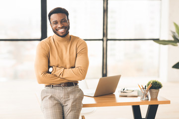 Successful black man sitting on desk at office
