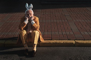 Sad old male with rabbit headgear in city stock photo