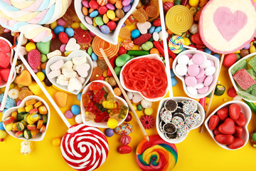 candies with jelly and sugar. colorful array of different childs sweets and treats on yellow...