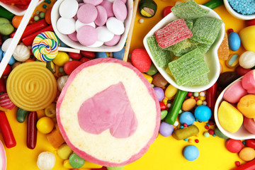 candies with jelly and sugar. colorful array of different childs sweets and treats on yellow background