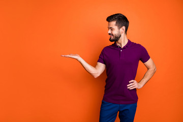 Photo of cheerful positive handsome man looking at empty space held with hand on waist in blue...