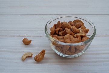 Cashews in a glass bowl on white wooden background