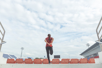 Woman runner's stretching her legs muscles before running at the stadium.
