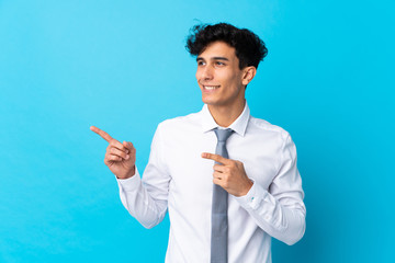 Young Argentinian businessman over isolated blue background pointing finger to the side