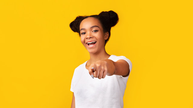 Happy black teenager choosing you over yellow background