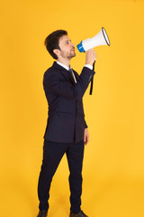 Fototapeta premium A man in a suit with a tie Handsome looking face with beard In the business man look Holding a megaphone To announce news or messages in the yellow background