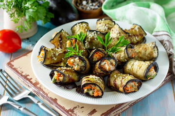 Appetizer stuffed with eggplant. Fried eggplant roll with chicken and vegetables in a plate on a wooden kitchen table.