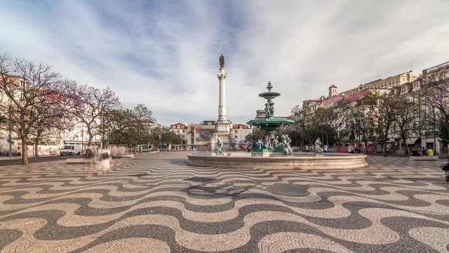 Rossio square with fountain and monument on column located at Baixa district timelapse hyperlapse in Lisbon, Portugal. Clouds on a blue sky and mosaic tiles
