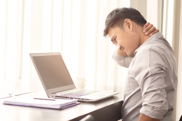 Asian office workers are suffering from neck pain from sitting on a laptop for a long time.Asian men are aching from hard work.