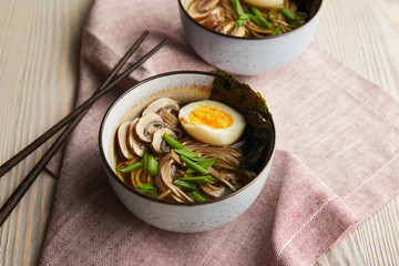 traditional spicy ramen in bowls with chopsticks on wooden table with napkin
