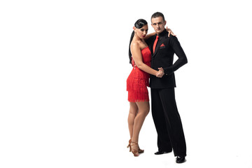 elegant couple of dancers looking at camera while performing tango on white background