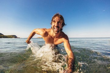 Fototapeta premium Handsome young man posing on the beach by the sea