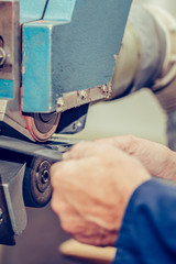Hands of an experienced shoemaker using special machine tool for making a shoes