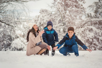 Fototapeta na wymiar Beautiful family photo of mom with her two sons enjoying winter time.