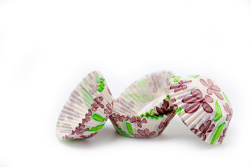 Paper, disposable muffin baking dish with a delicate floral pattern, shot on a white background