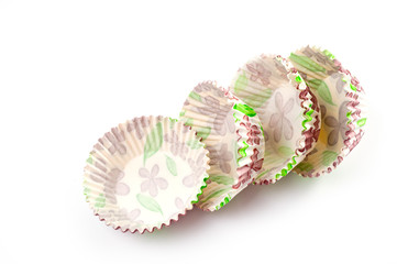 Paper, disposable muffin baking dish with a delicate floral pattern, shot on a white background